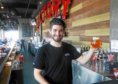 Keegan Phalen holds up a cold draft beer at the new Victory Brewing Co. in Kennett Square. Victory opened for business on Monday. (Fran Maye -- For Main Line Suburban Life)